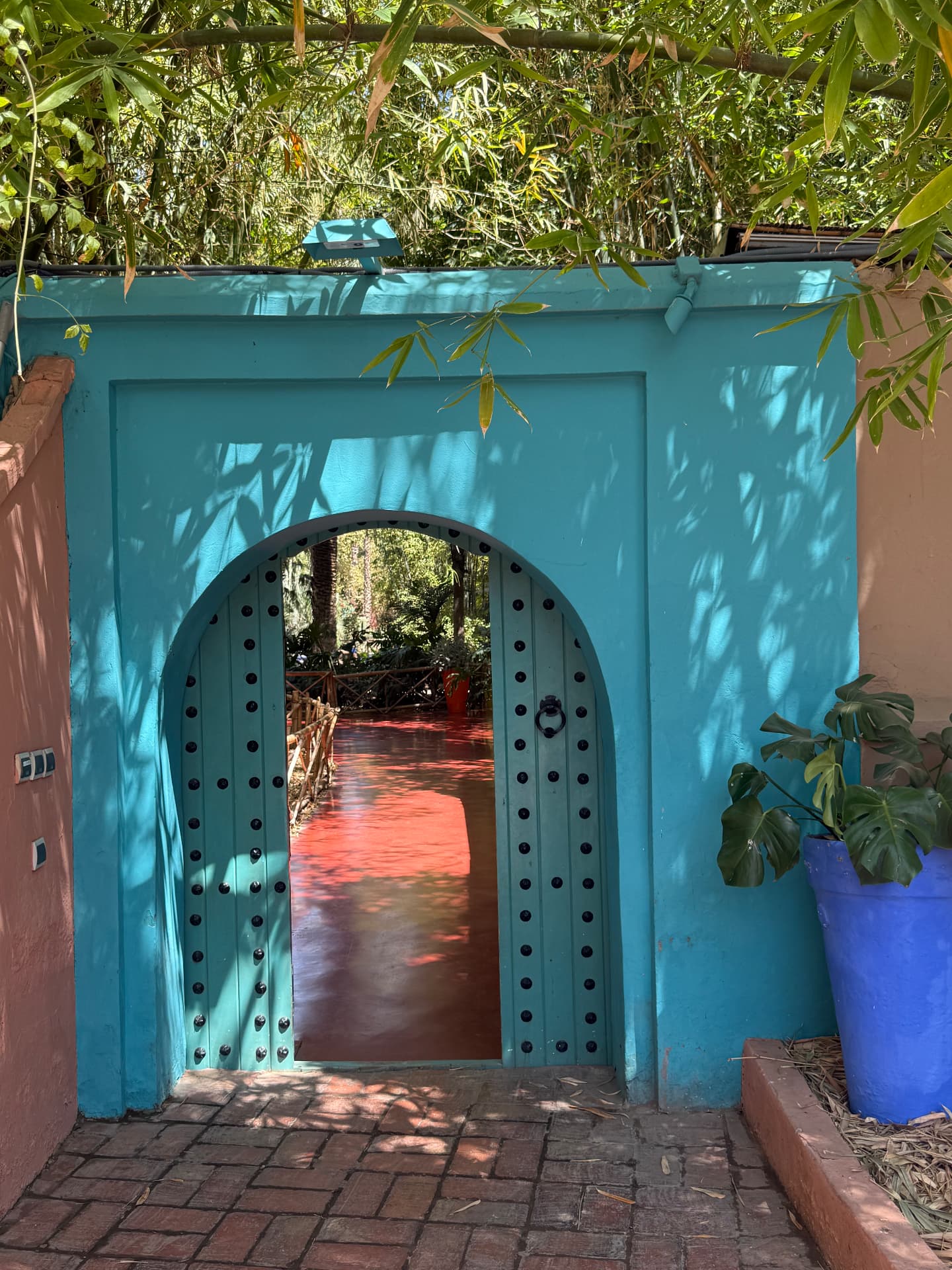 A teal arched doorway framing a garden path